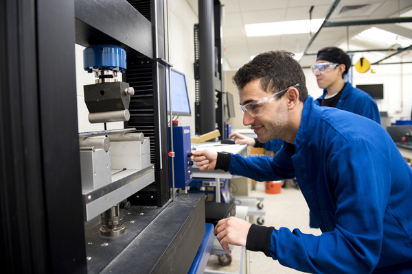 A third-year student, conducts a three-point bend test on a piece of aluminum round bar in the Soils and Materials Lab.