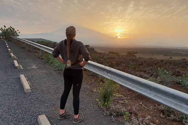 girl in jogging clothes with hands on him on road looking out at sunset