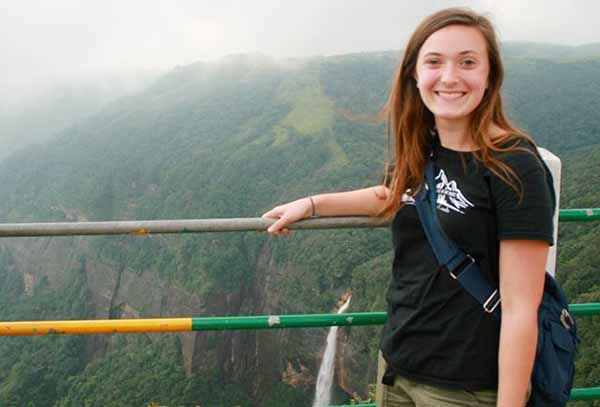 student on bridge overlooking mountains in India