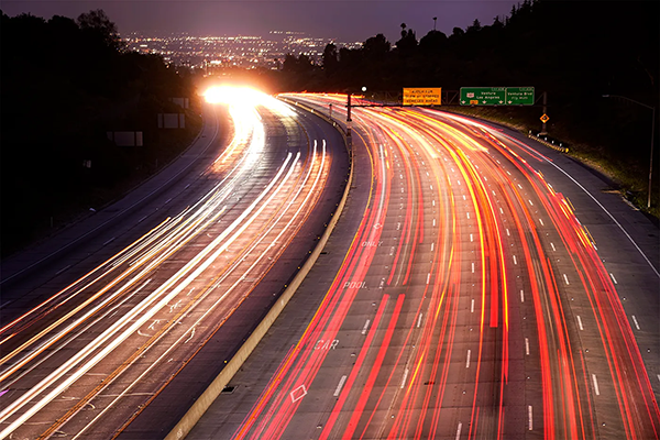 time-lapse of a highway; the left is white from the headlights and the right is red from taillights